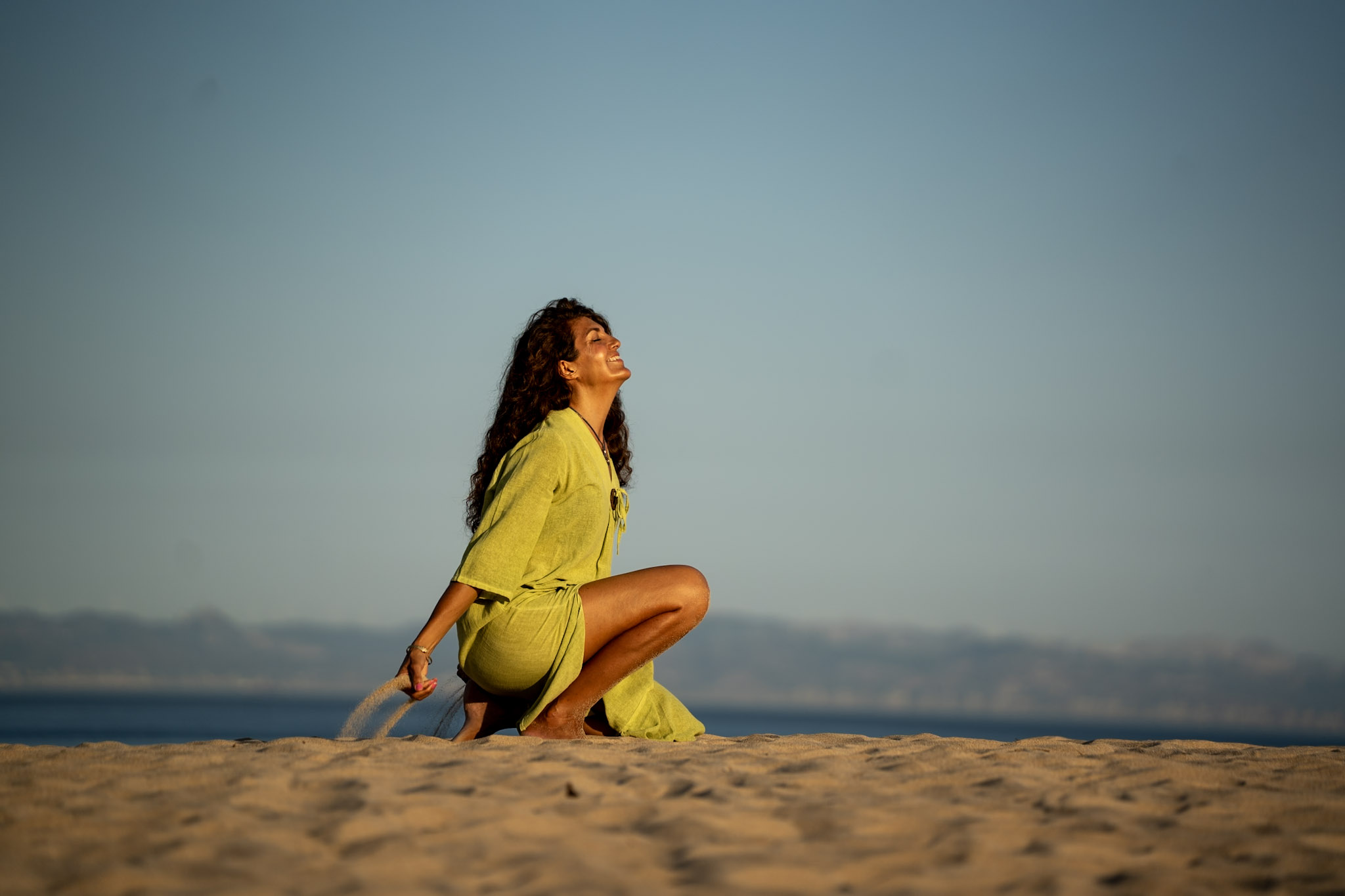 Paz Calap sentada en la arena con vestido verde, serena y suficiente